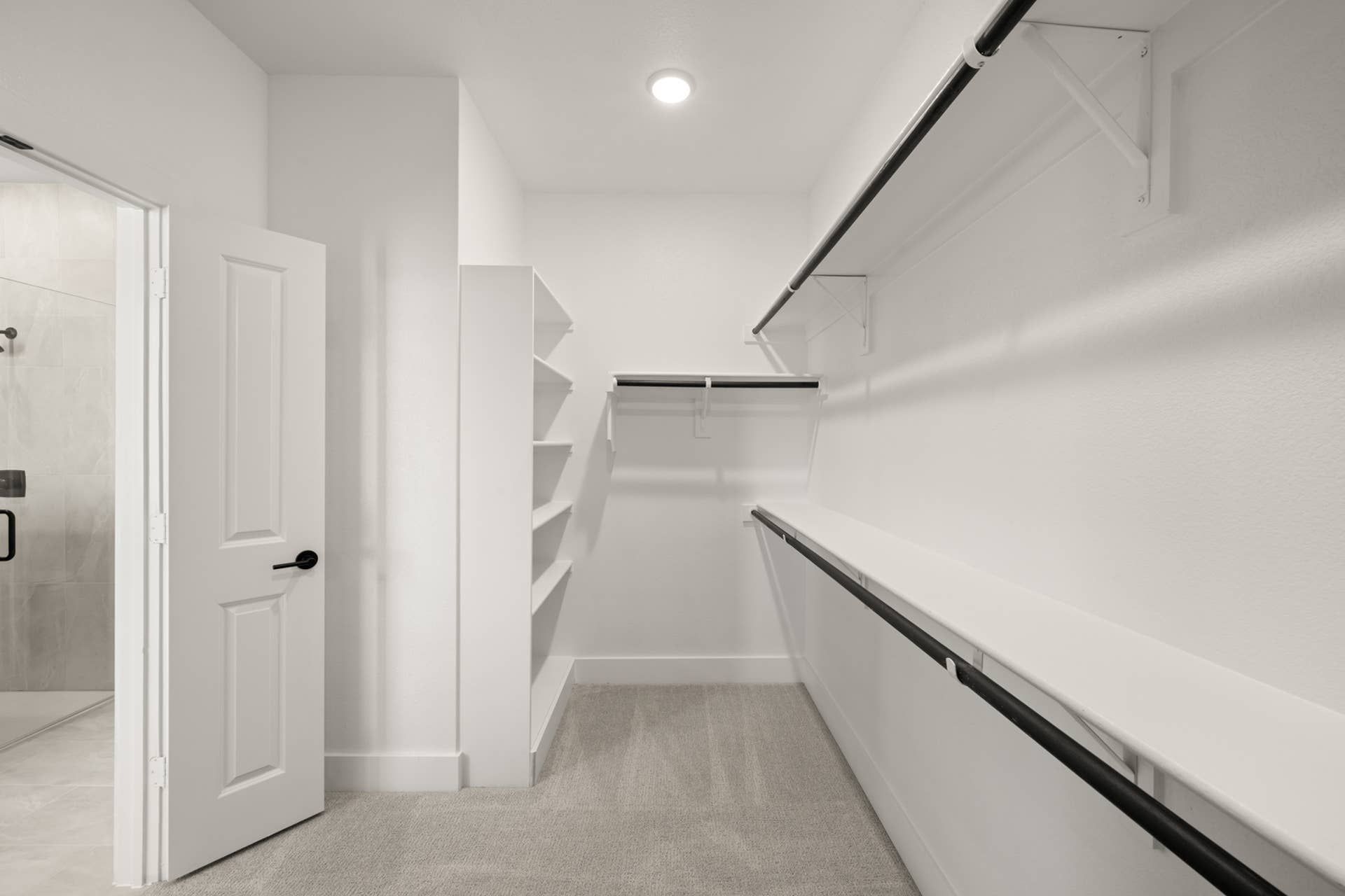 Spacious walk-in closet with white shelving and hanging rods in primary suite.