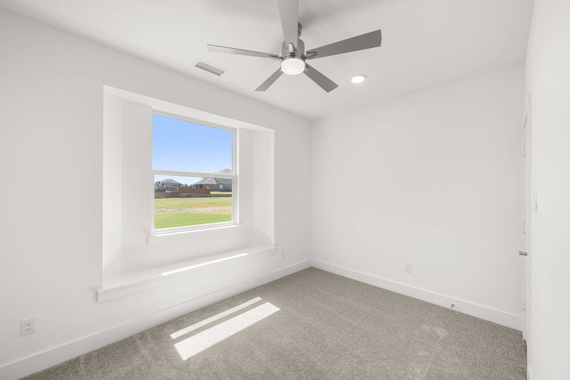 Bright study room with large window and ceiling fan.
