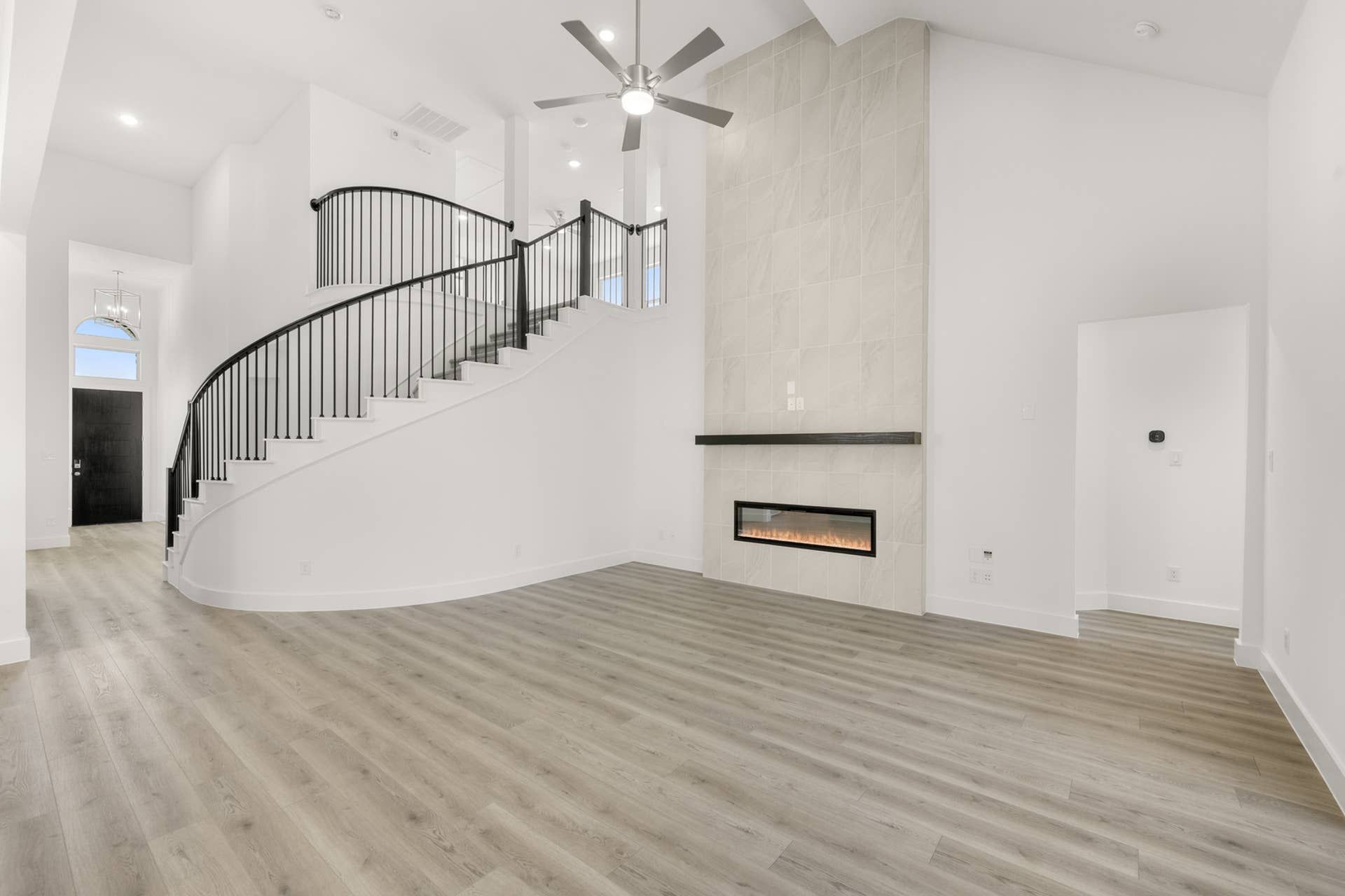 Spacious living room with modern fireplace and elegant curved staircase.