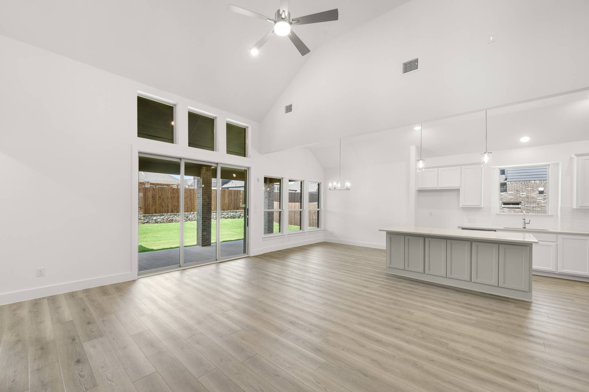Spacious living room with vaulted ceilings and large windows overlooking a green backyard.