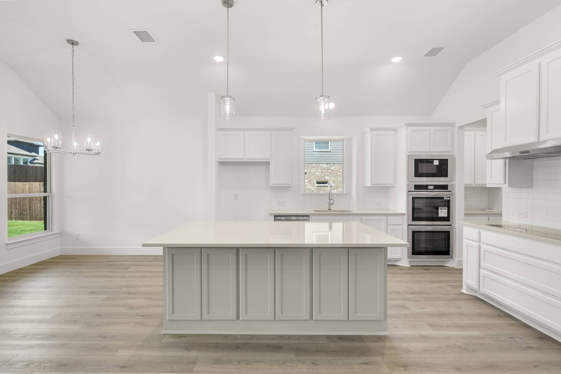 Modern kitchen with large island, white cabinetry, and stainless steel appliances.