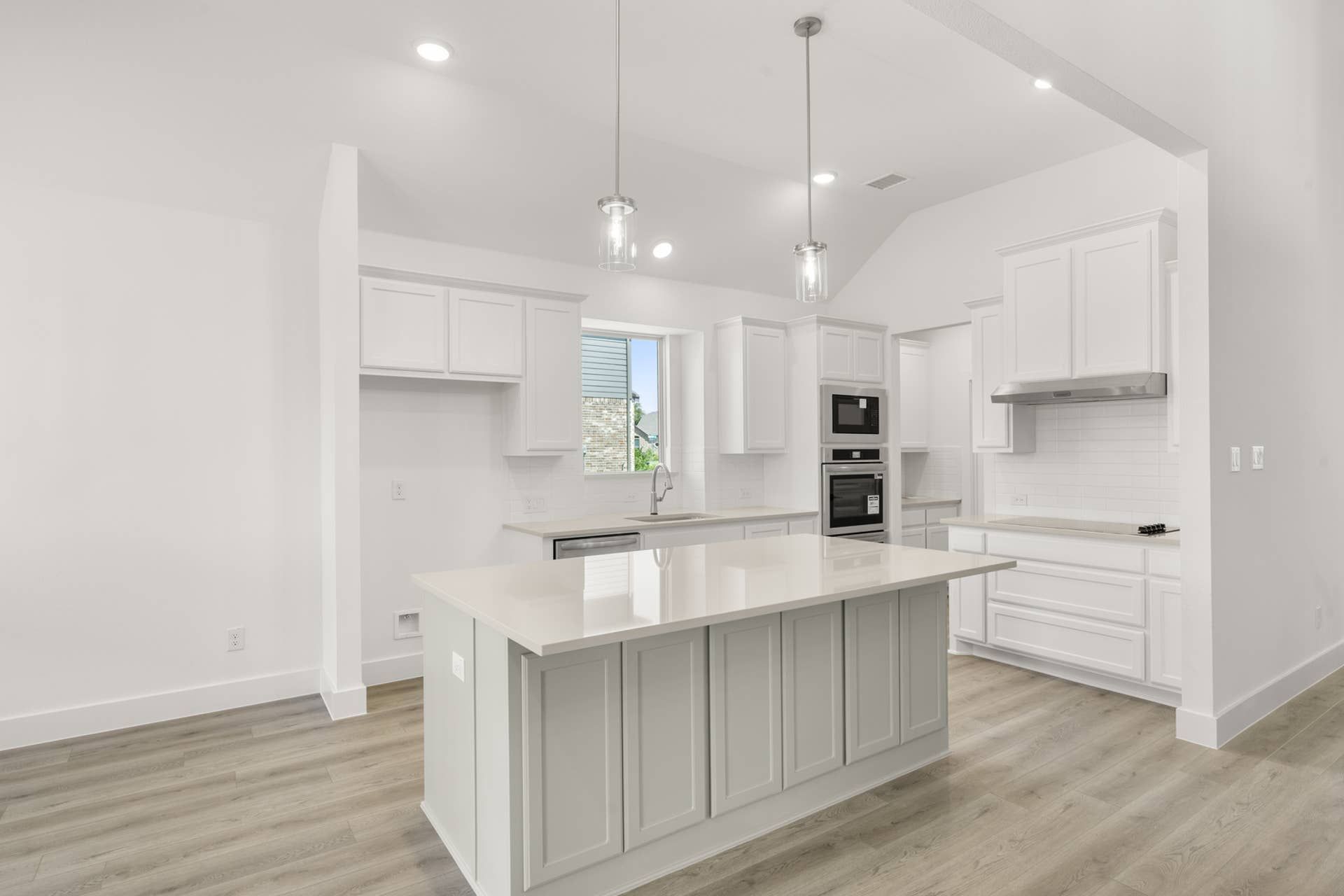 Modern kitchen with white cabinetry, island, and pendant lighting.