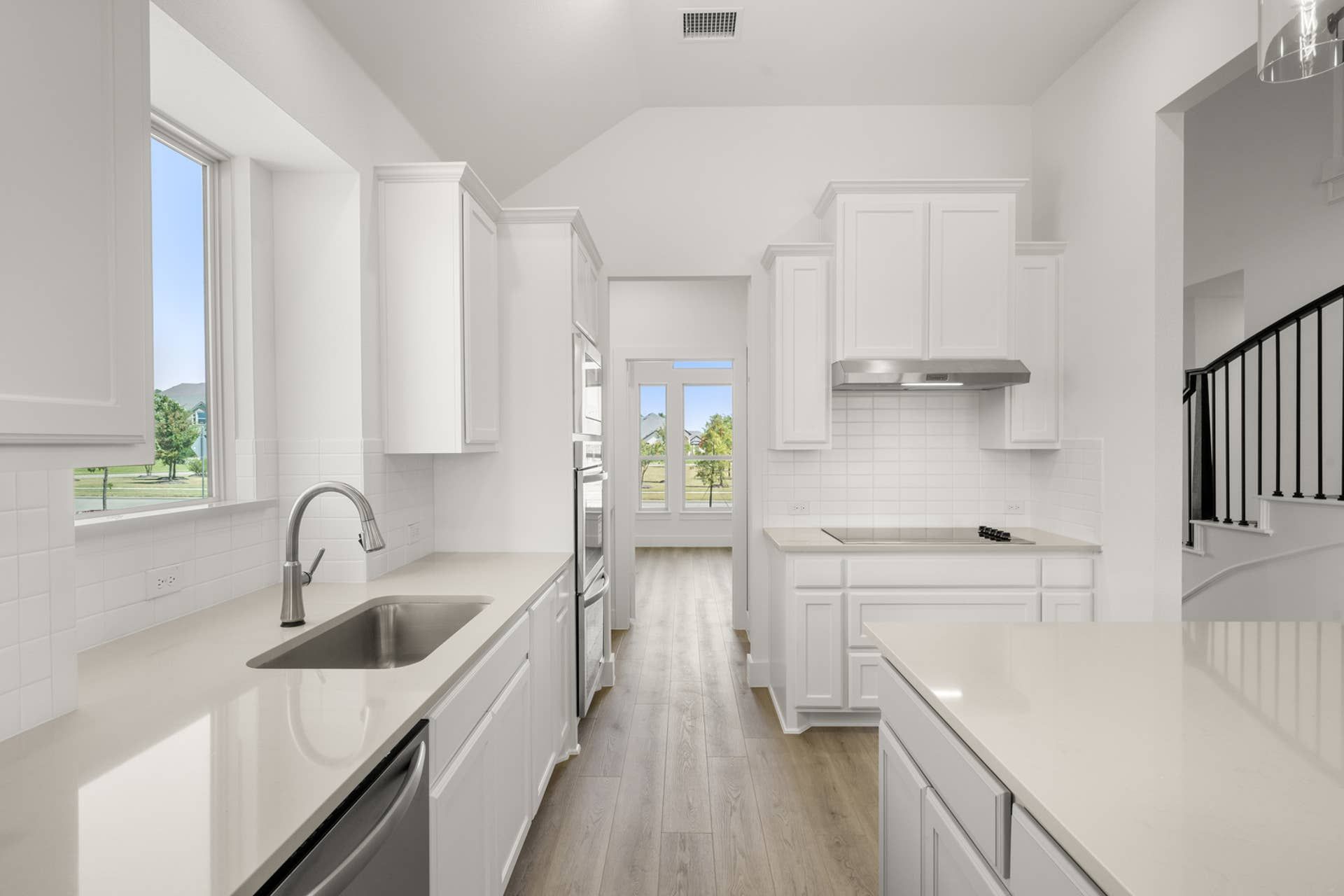Bright modern kitchen with white cabinetry and stainless steel fixtures.