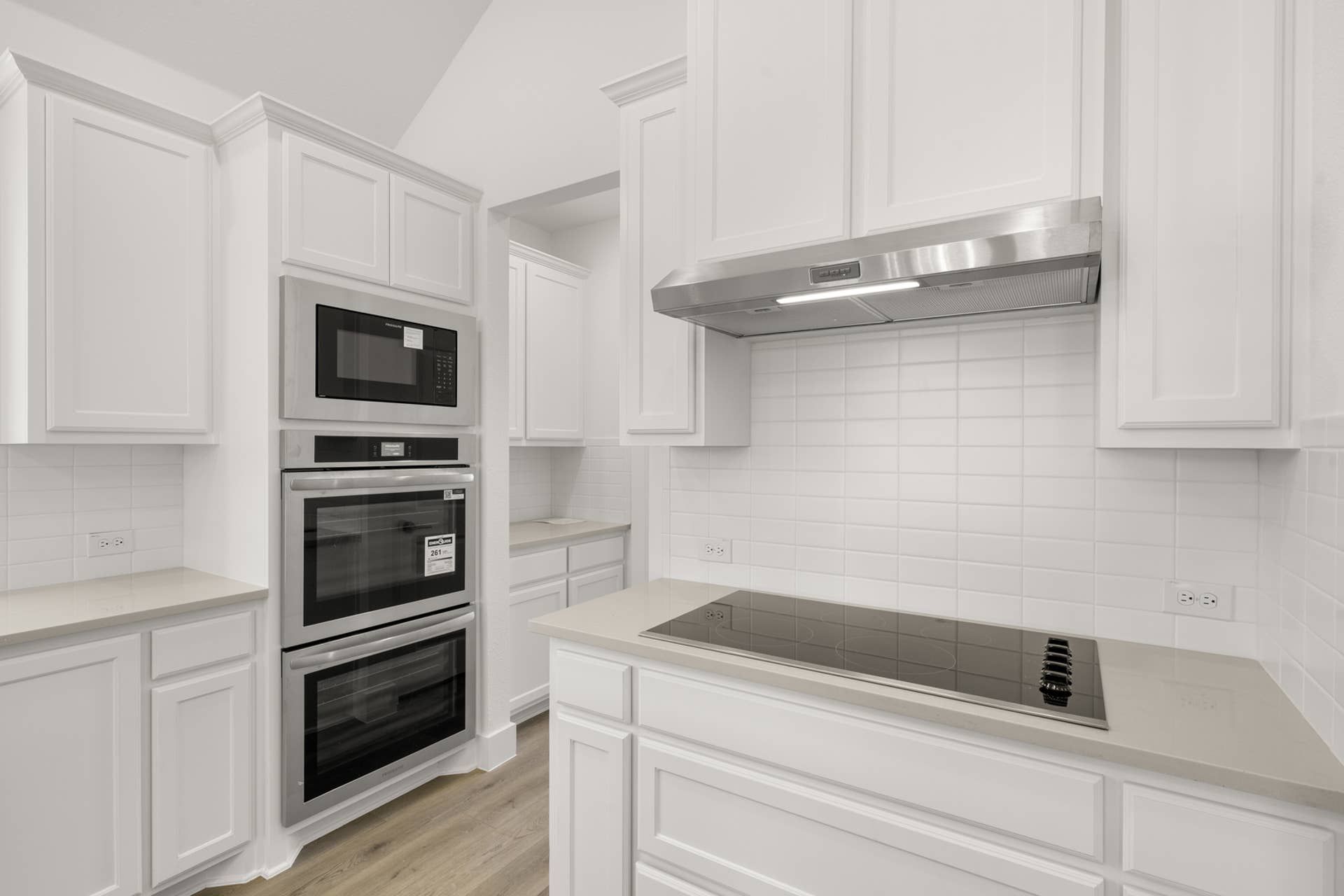 Modern kitchen with white cabinetry, stainless steel appliances, and tile backsplash.