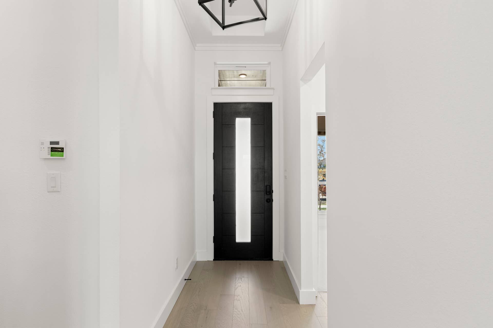 Modern entryway with black door and geometric ceiling light fixture.