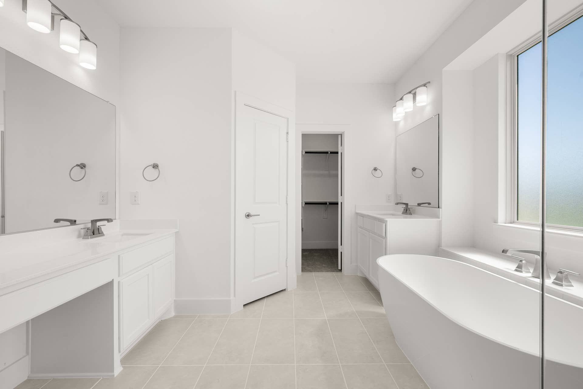 Elegant primary suite bathroom with dual vanities, soaking tub, and walk-in closet.