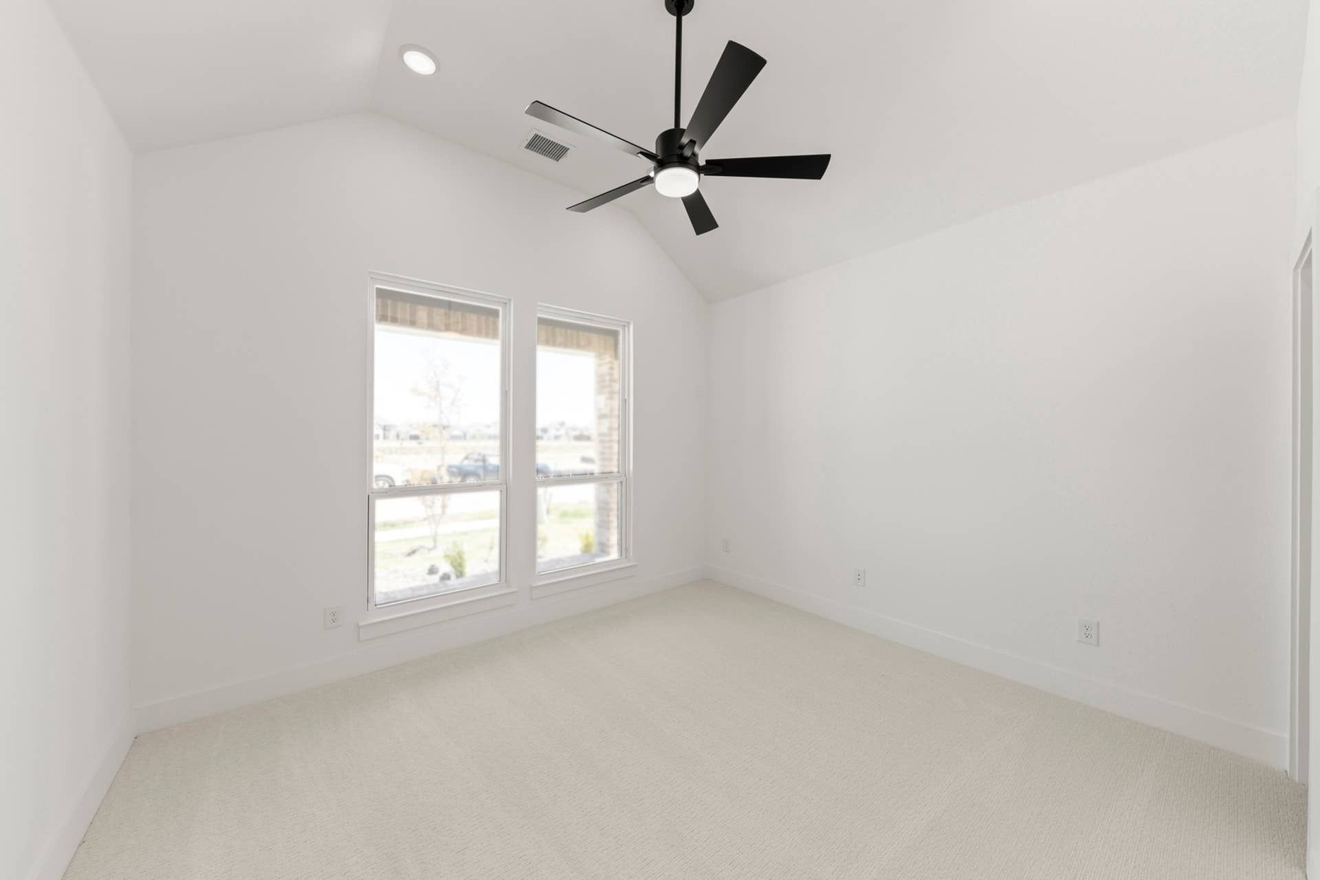 Spacious bedroom with large windows and modern ceiling fan.