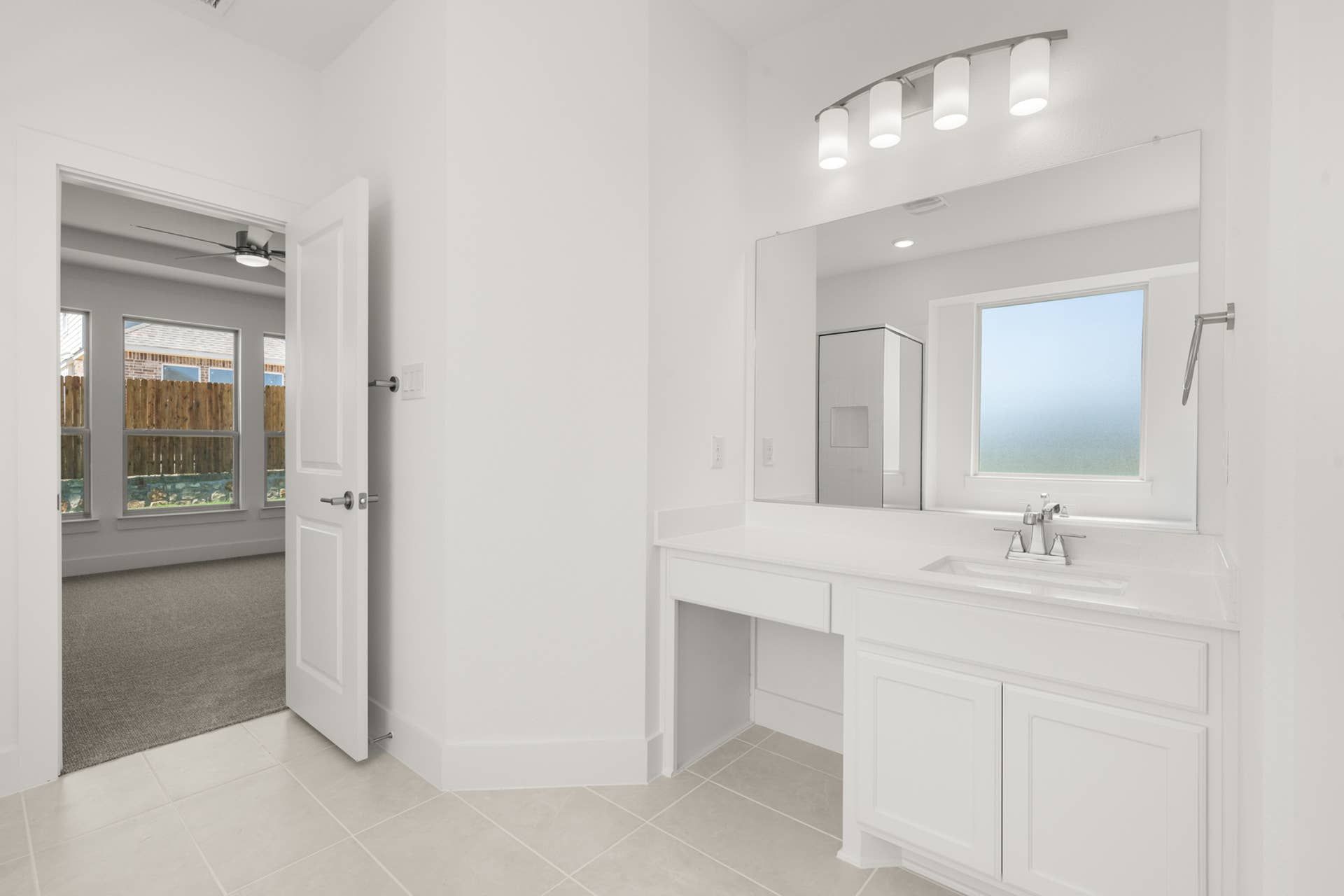 Modern bathroom vanity with large mirror and adjacent bedroom view.
