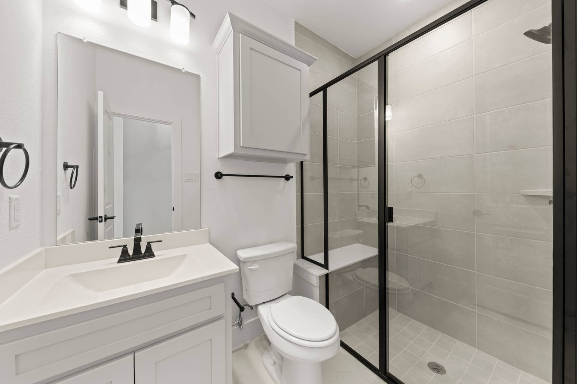 Modern bathroom with glass shower, white vanity, and sleek fixtures.