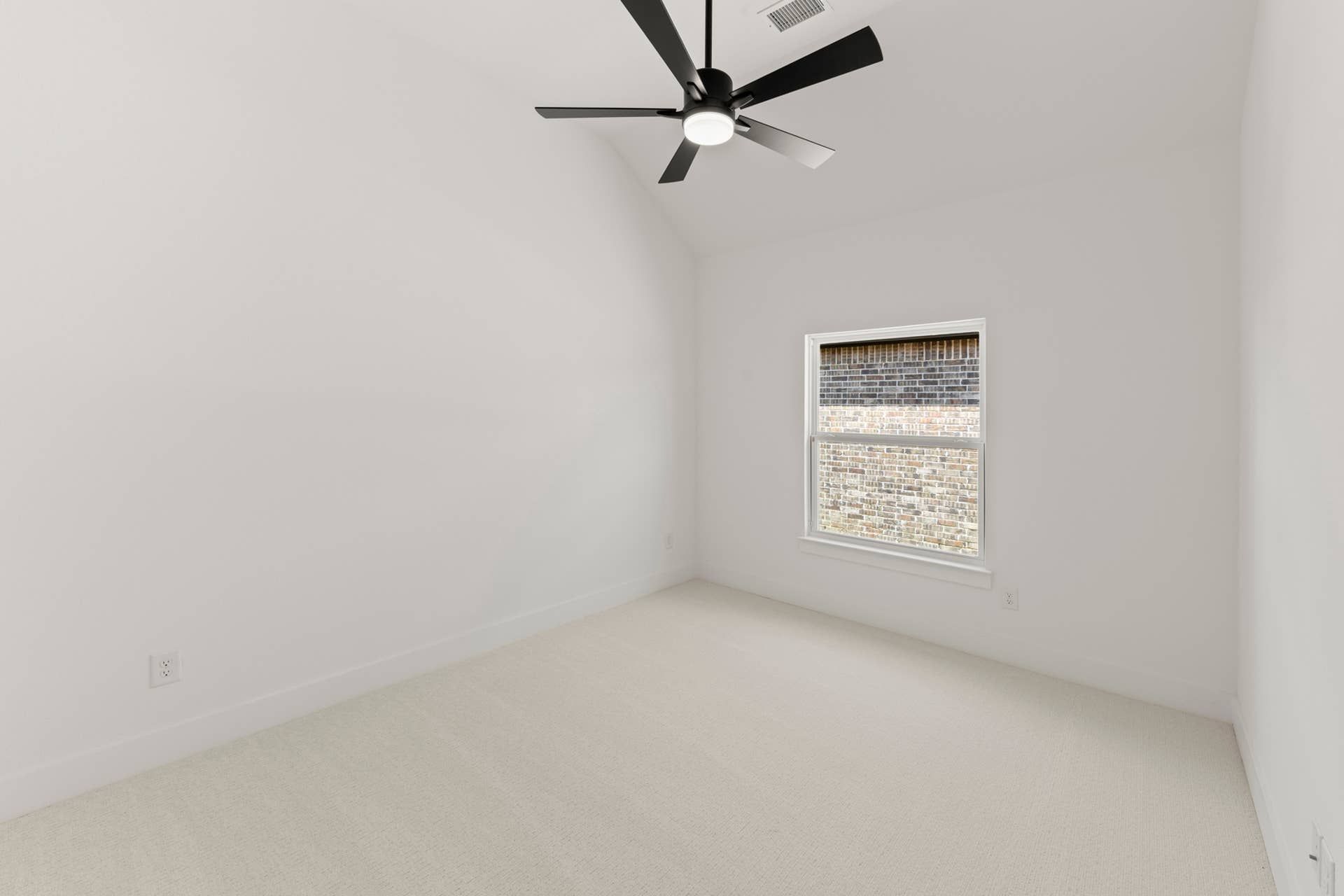 Minimalist bedroom with white walls, ceiling fan, and carpeted floor.
