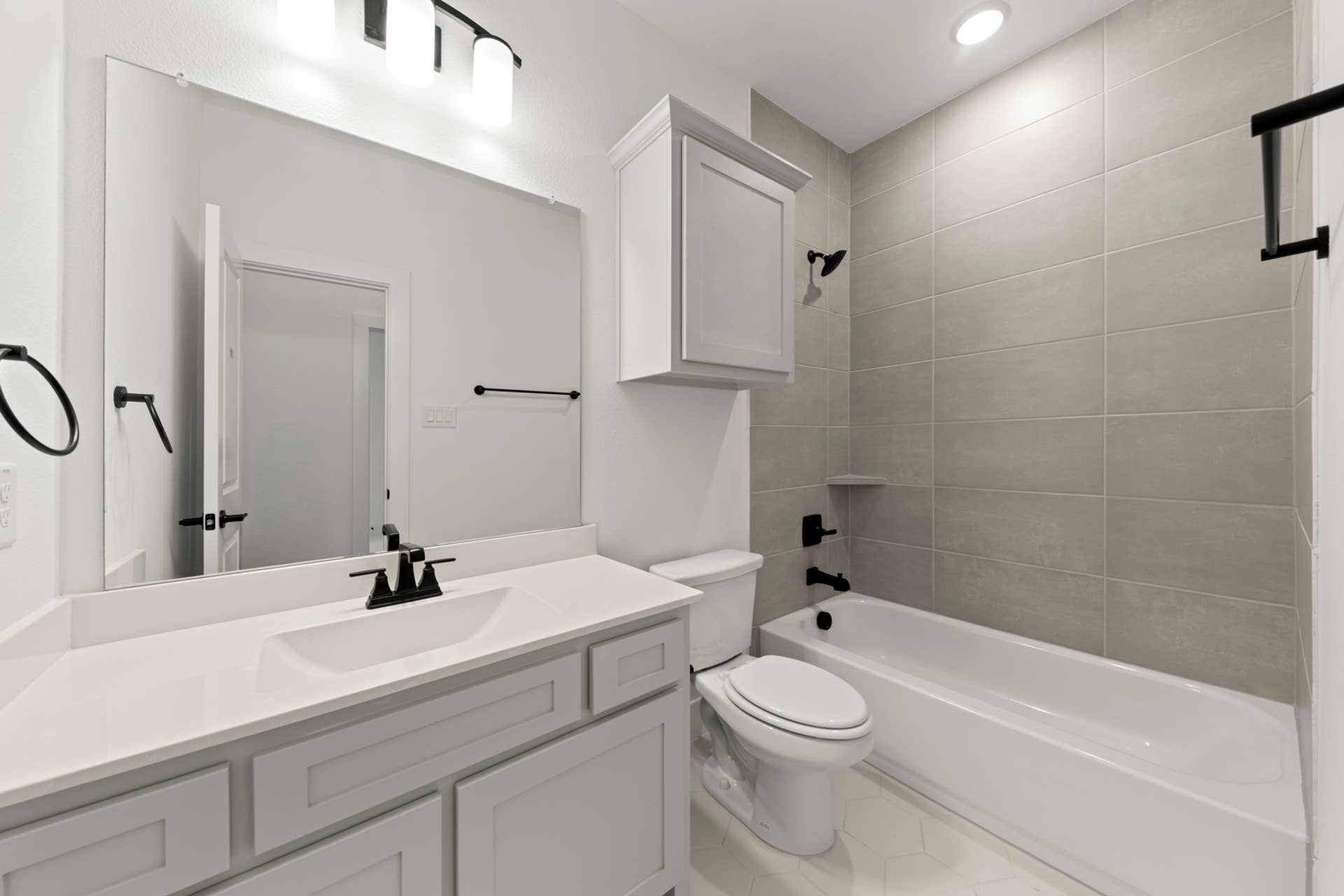 Modern bathroom with white vanity and gray tiled shower.