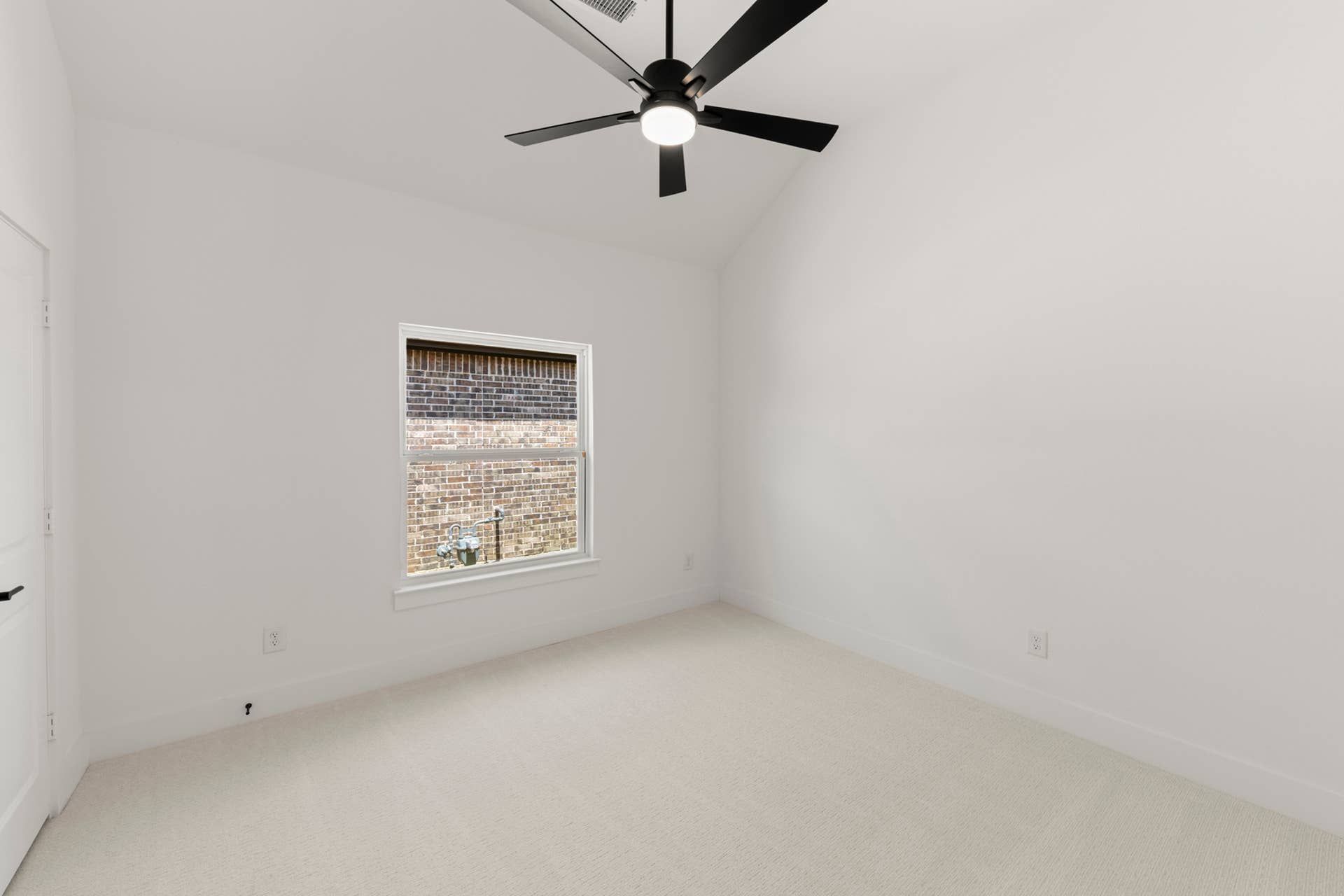 Bright bedroom with vaulted ceiling, ceiling fan, and carpet flooring.