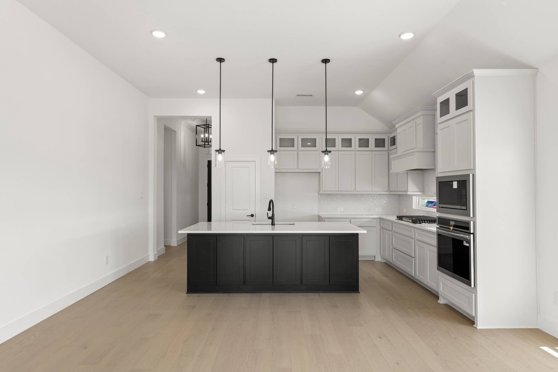 Modern kitchen with island, pendant lighting, and light wood flooring.