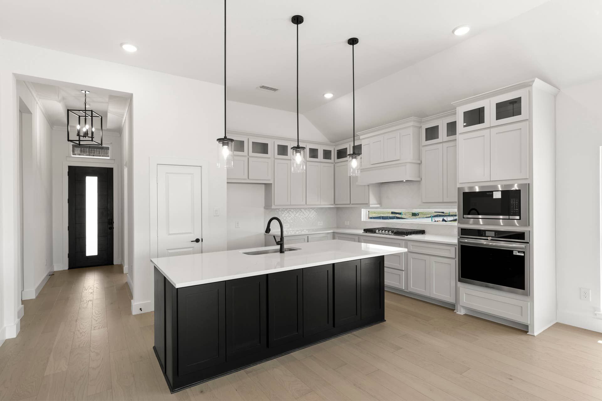 Modern kitchen with black island, white cabinets, and pendant lighting.