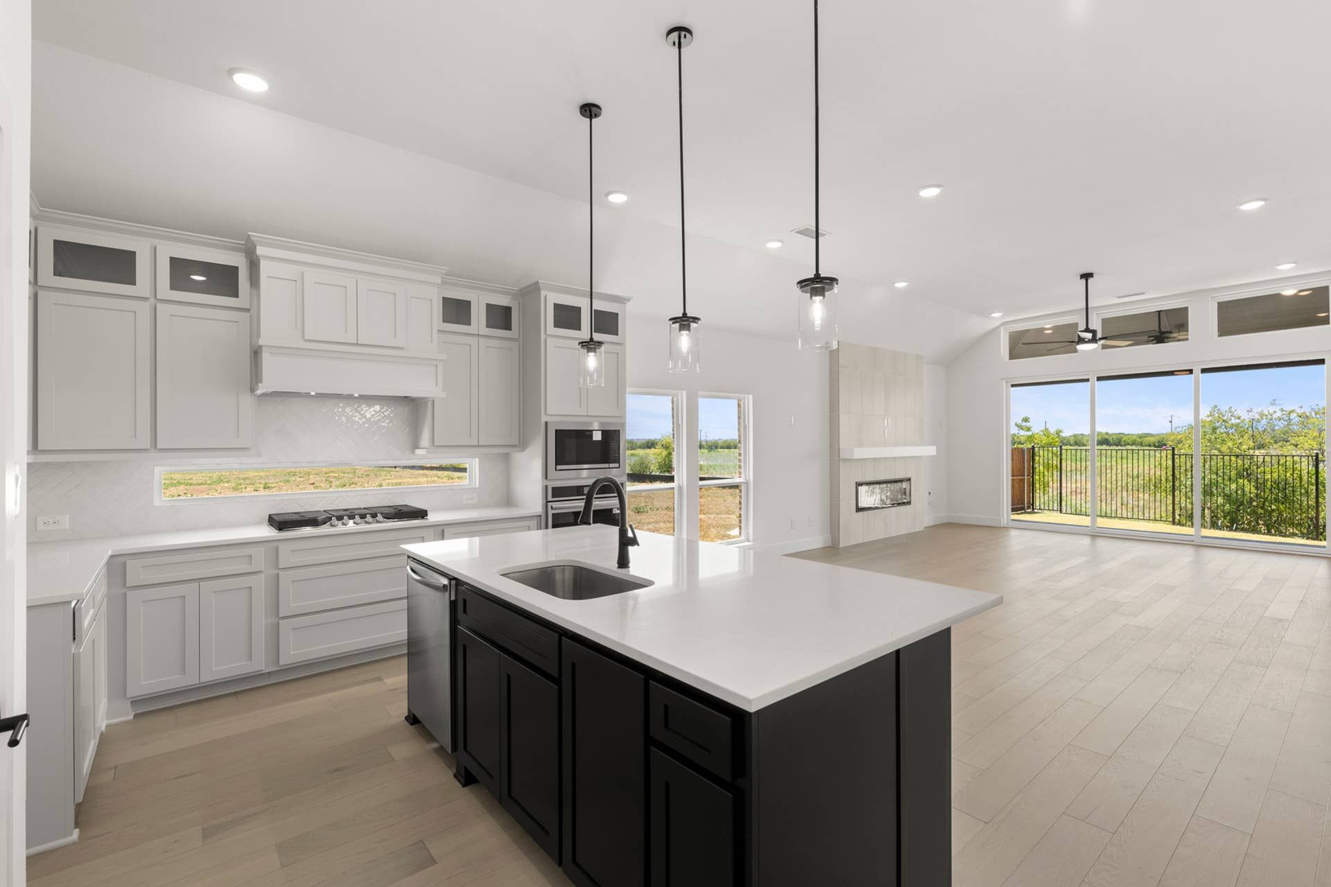 Modern kitchen with island, pendant lights, and large windows overlooking a scenic view.