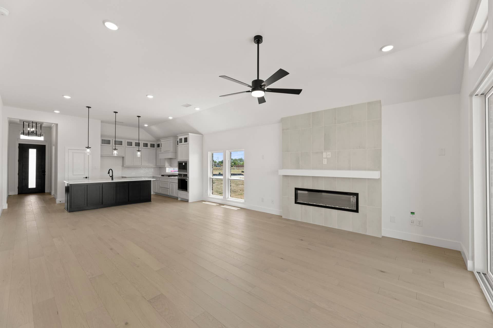 Spacious modern kitchen and living area with fireplace and ceiling fan.