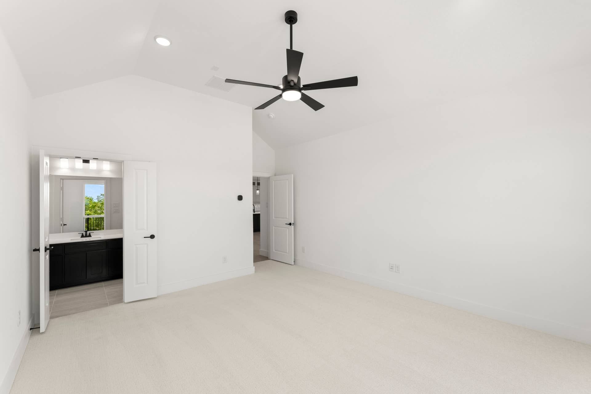 Spacious bedroom with ceiling fan and en suite bathroom entrance.