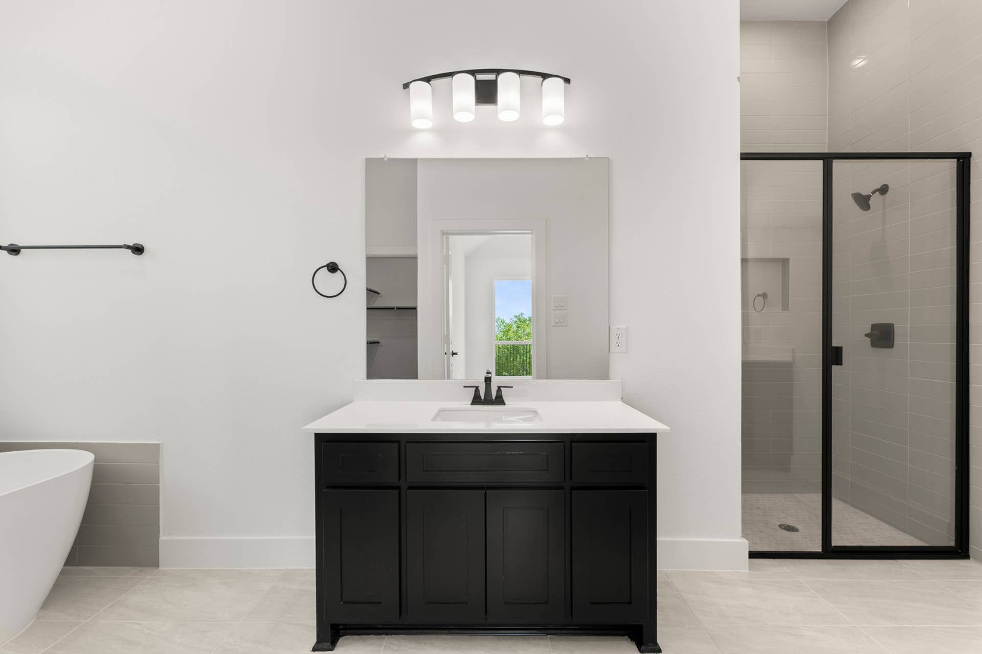 Modern bathroom with black vanity, frameless shower, and freestanding tub.