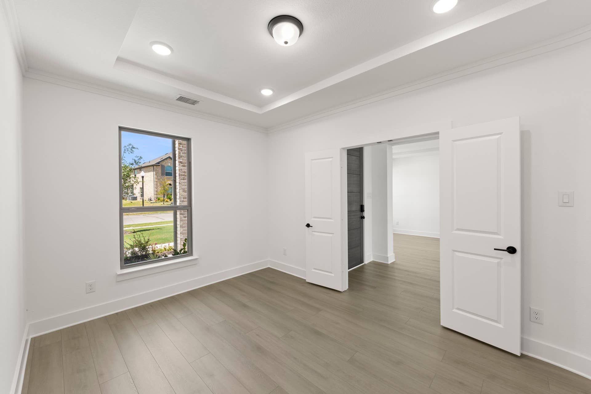 Bright study room with hardwood floors and double doors.