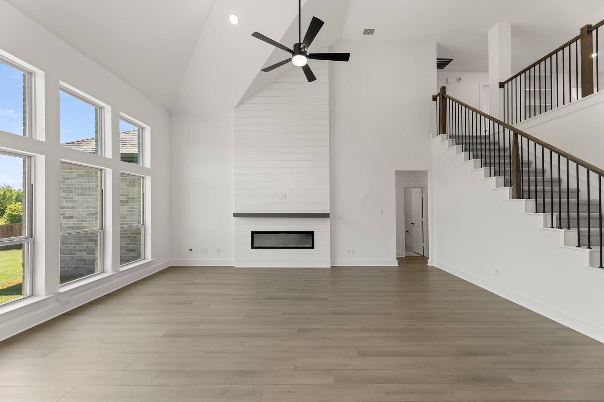 Spacious living room with vaulted ceiling, modern fireplace, and large windows.