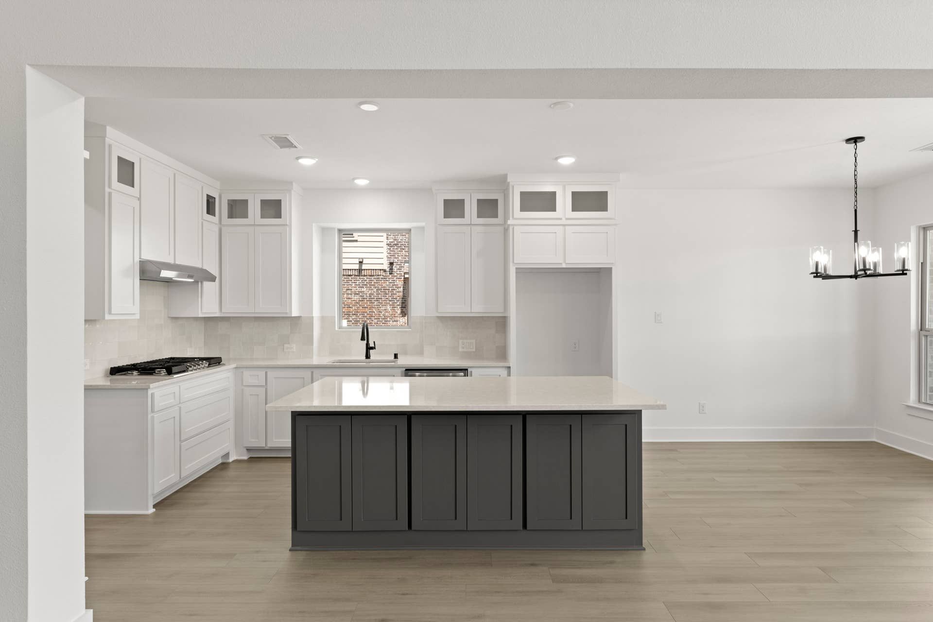 Spacious modern kitchen with island, white cabinetry, and elegant lighting.
