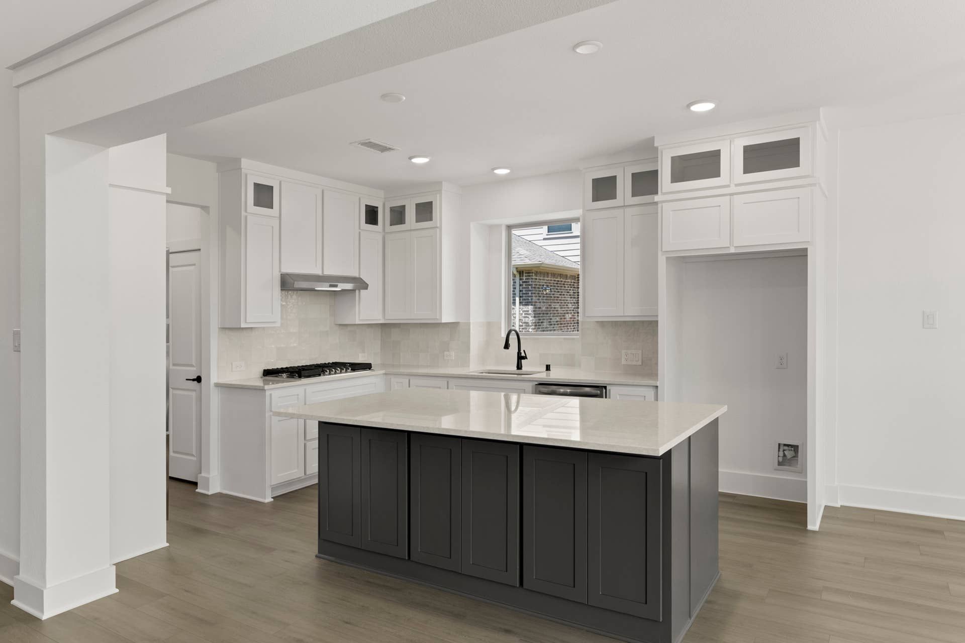 Modern kitchen with white cabinetry, island, and hardwood floors.