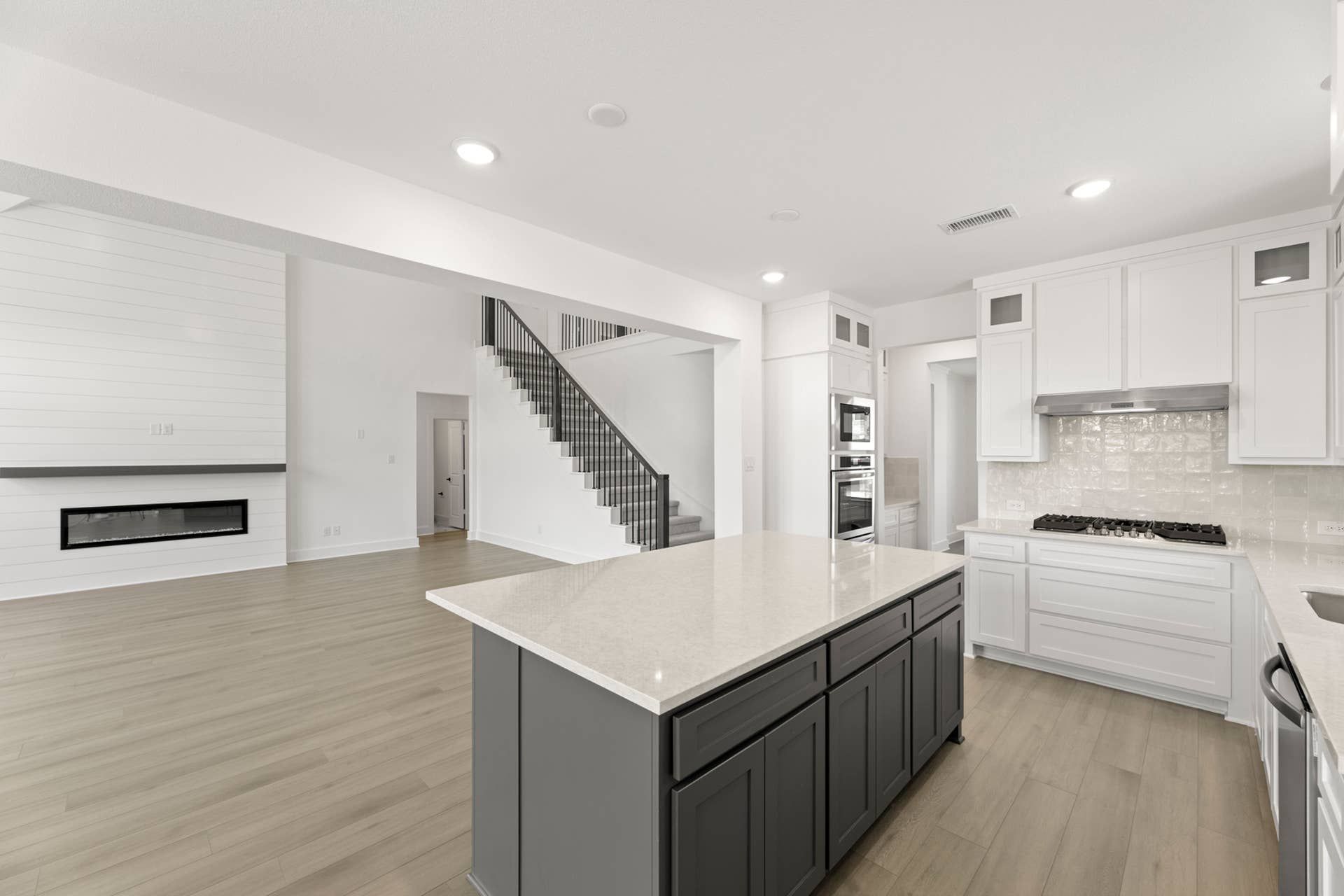 Modern kitchen with island, white cabinetry, and open living space.