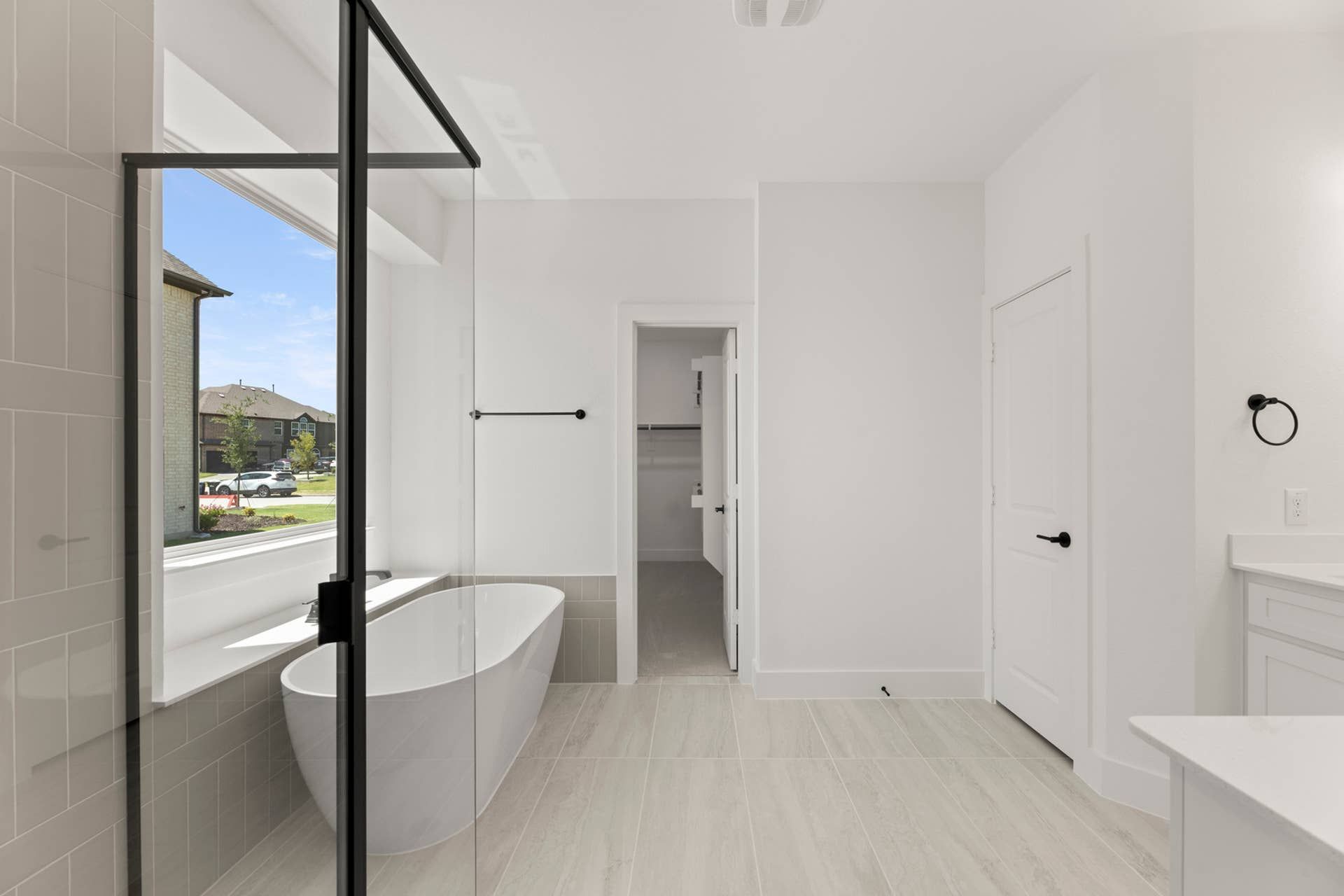 Spacious modern bathroom with freestanding tub and large window view.