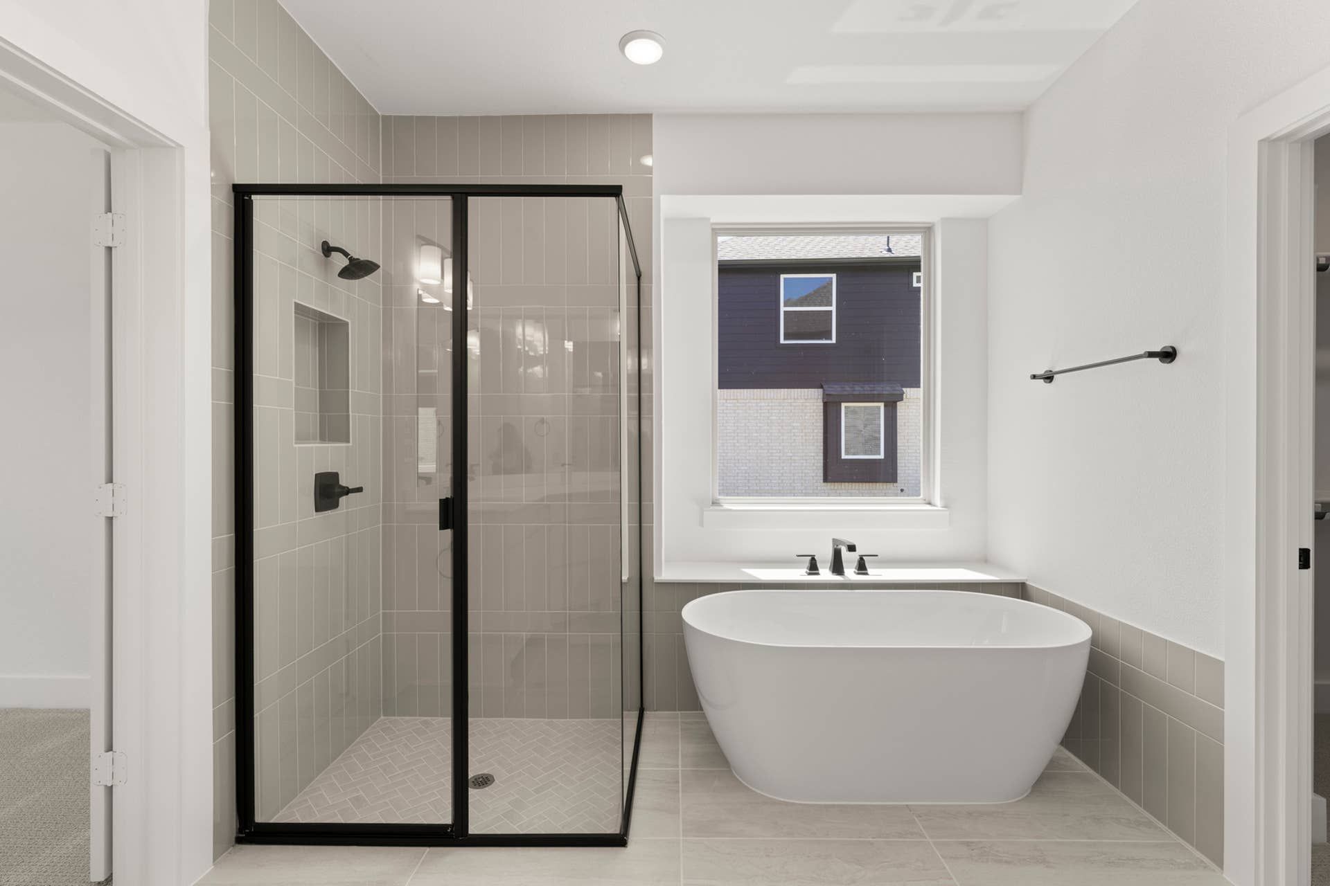 Modern bathroom with glass shower and freestanding tub near large window.