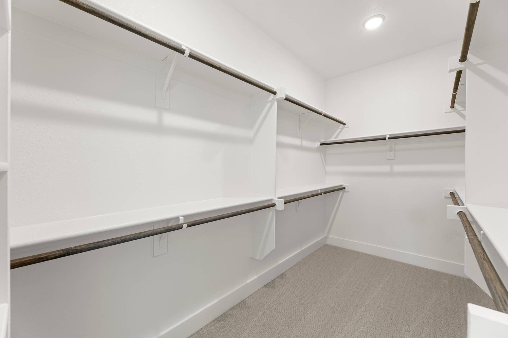 Spacious walk-in closet with multiple hanging rods and white shelving.