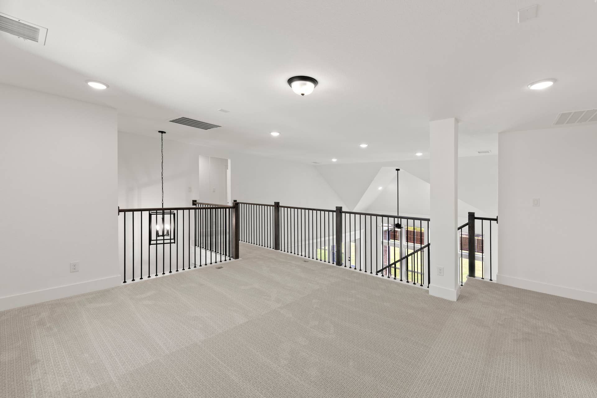 Spacious loft area with carpet flooring and modern railing.
