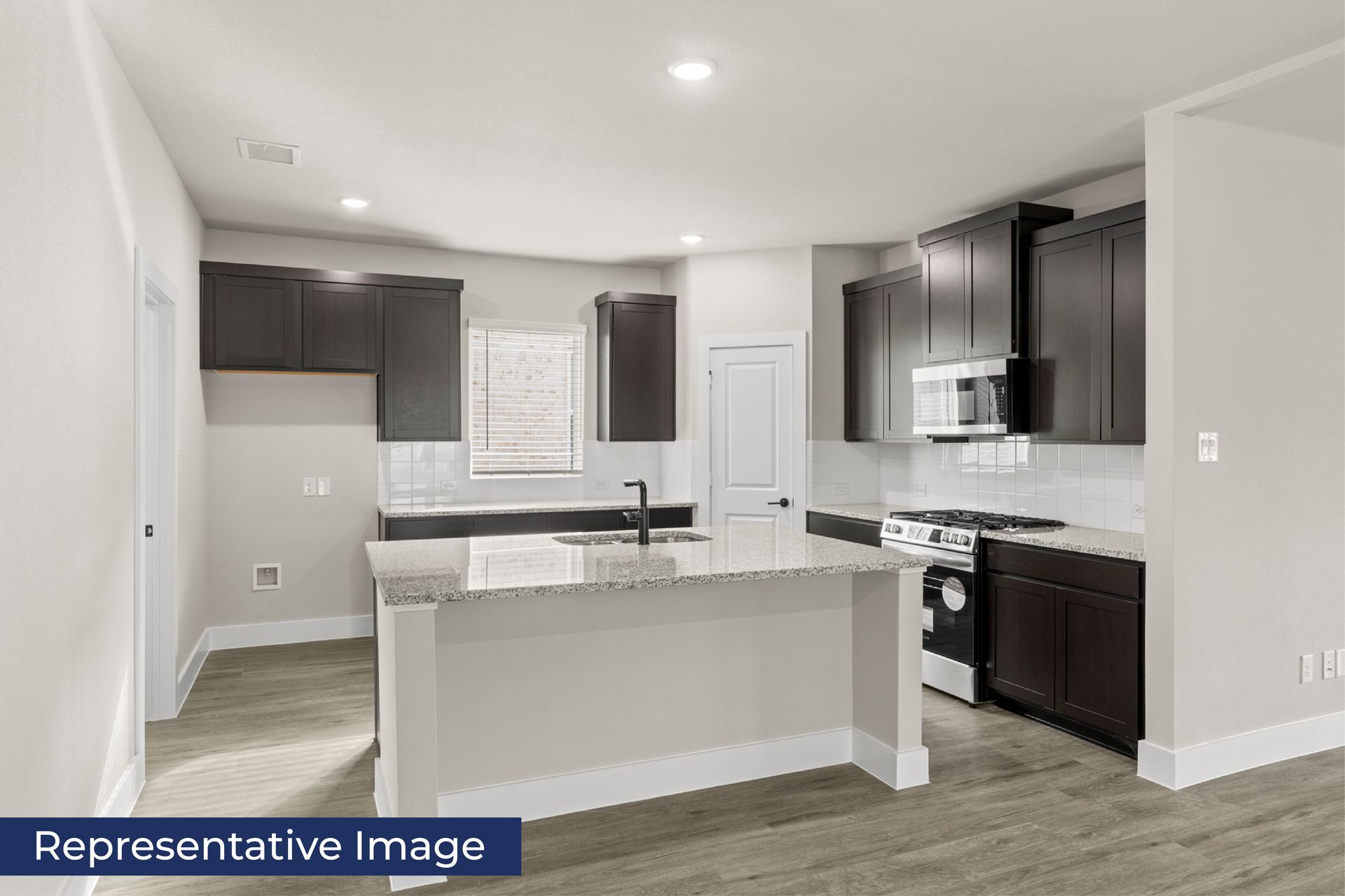 Modern kitchen with dark cabinets, granite countertops, and stainless steel appliances.