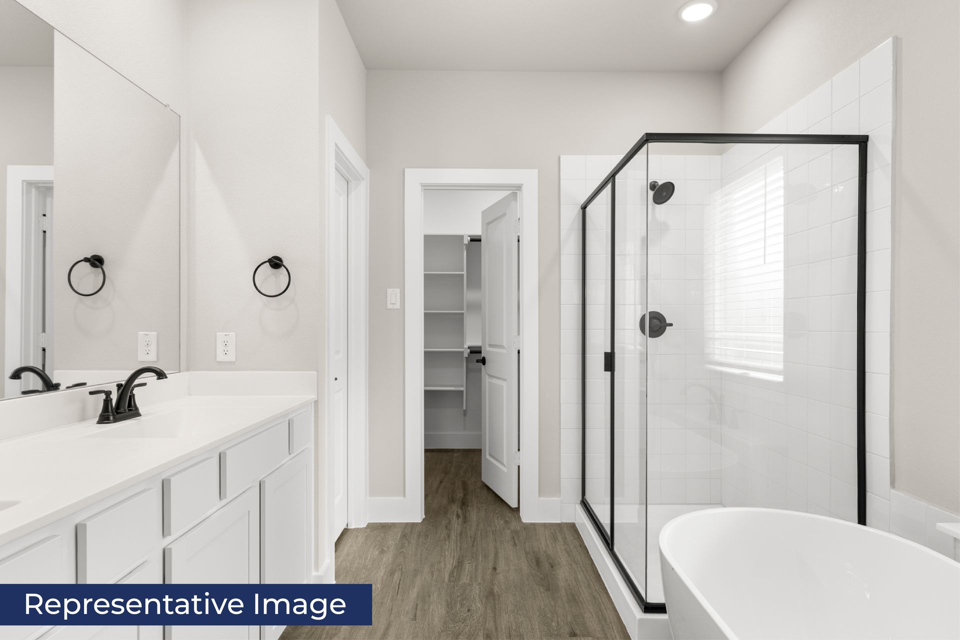Modern bathroom with glass shower, bathtub, and double sink vanity.