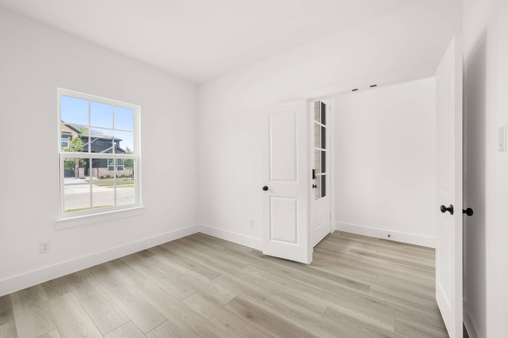 Bright study room with hardwood floors and double French doors.
