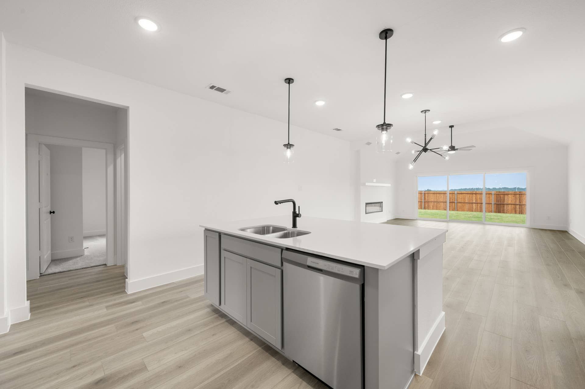 Modern kitchen interior with island, pendant lighting, and open floor plan.
