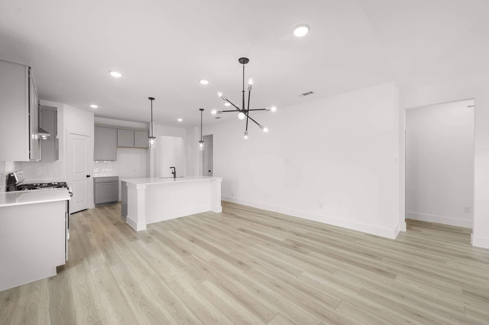 Modern kitchen and dining area with pendant lighting and hardwood floors.