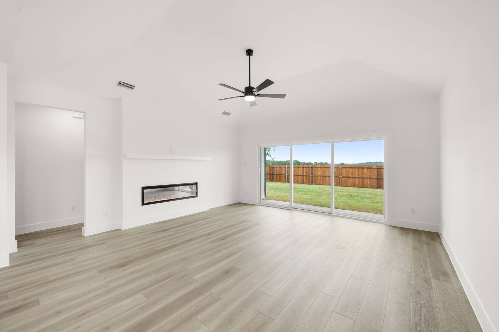 Spacious living room with modern fireplace and large sliding glass doors to backyard.