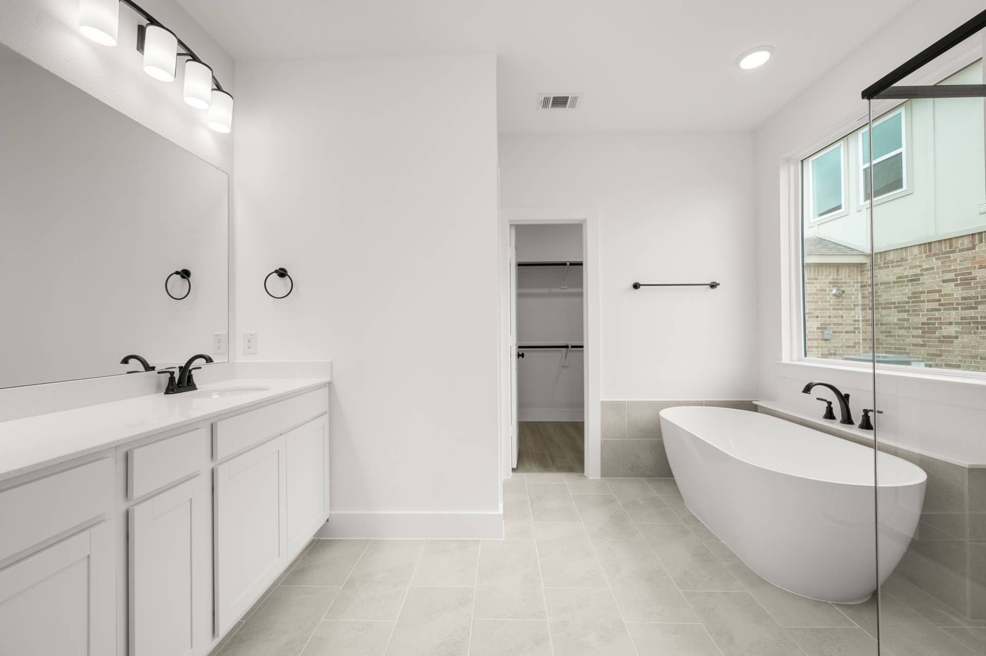 Spacious modern bathroom with freestanding tub, dual vanity, and large mirror.