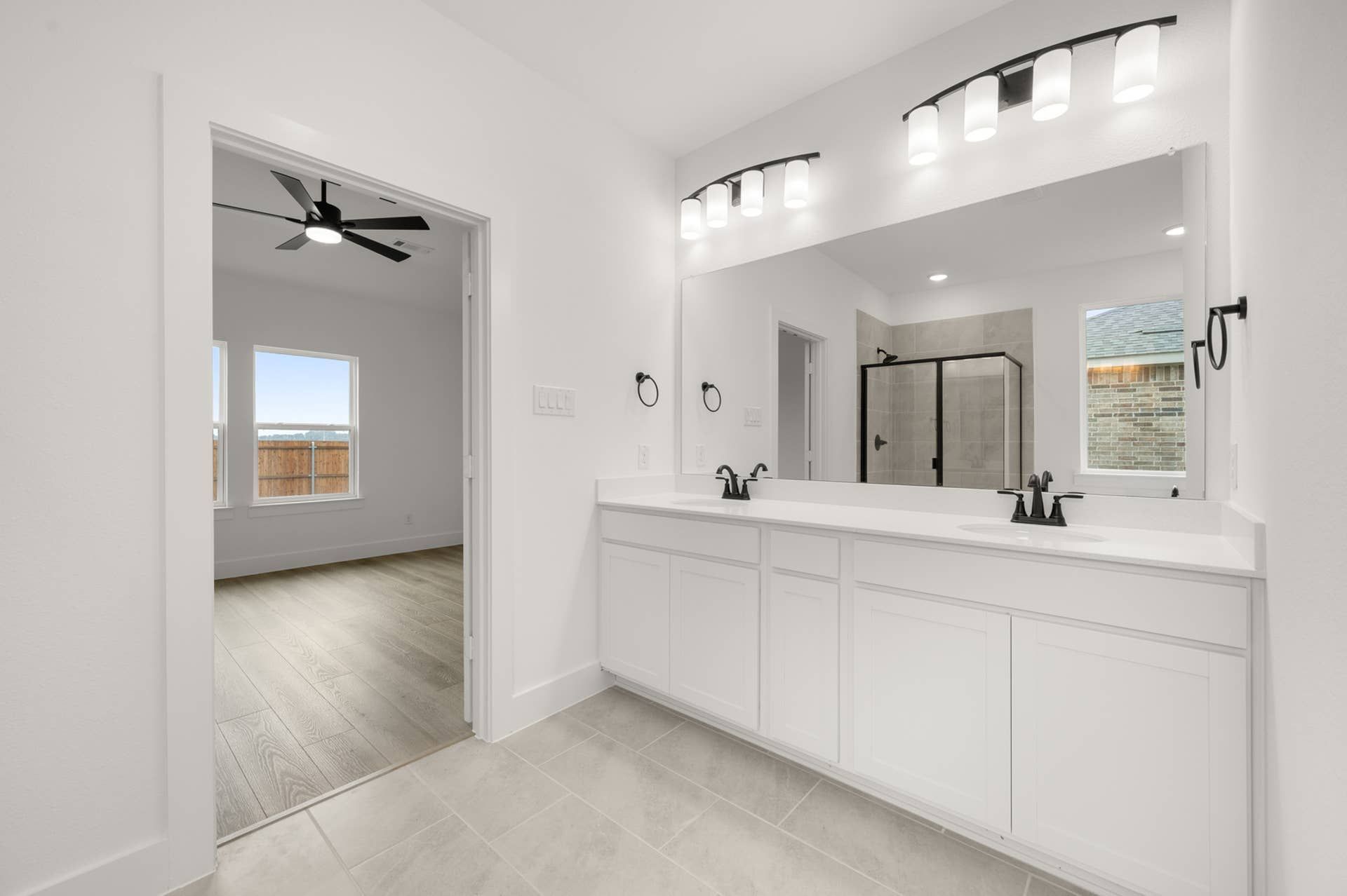 Modern bathroom with dual sinks, large mirror, and glass shower enclosure.