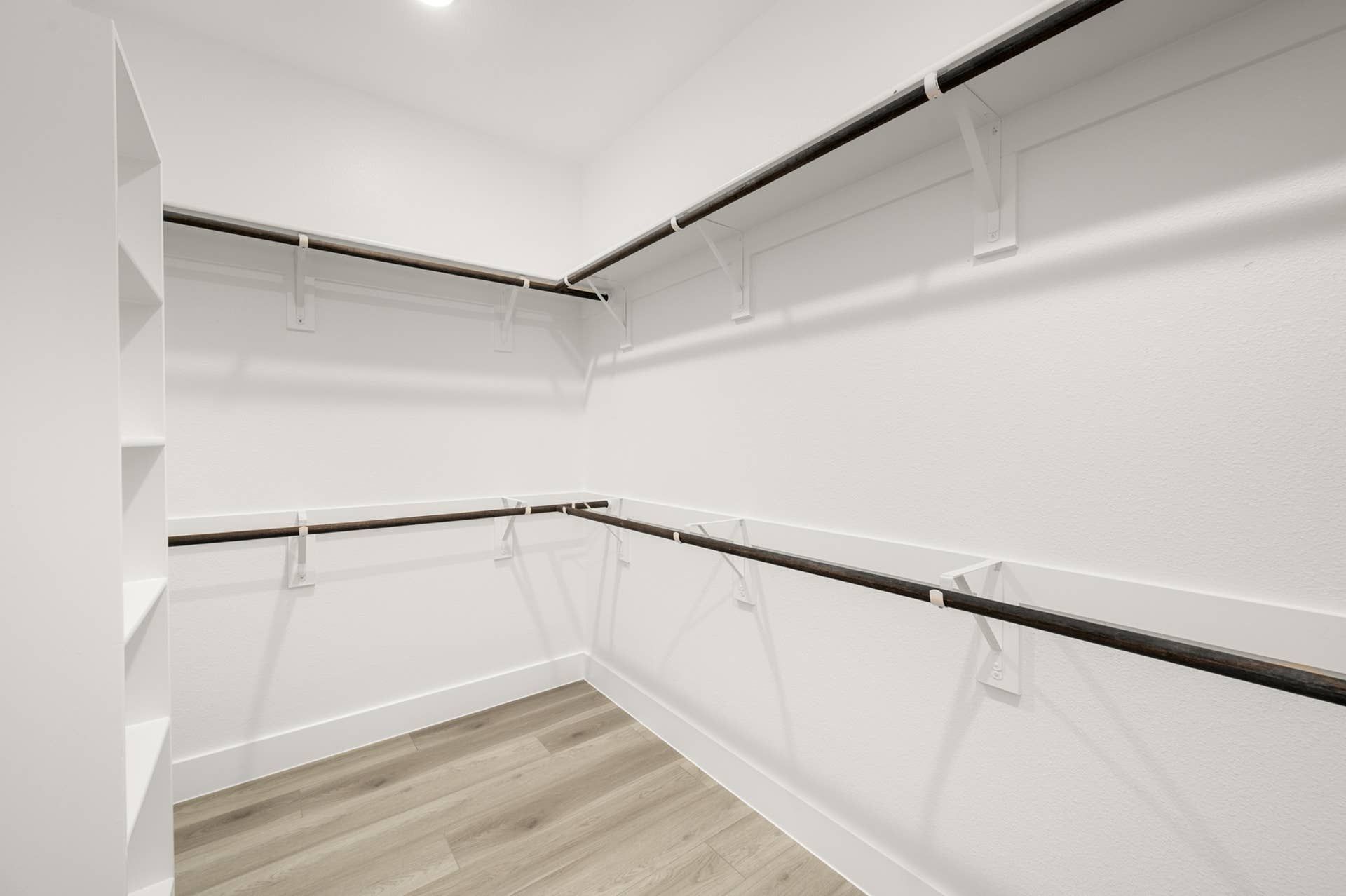 Spacious walk-in closet with wooden rods and shelving units.