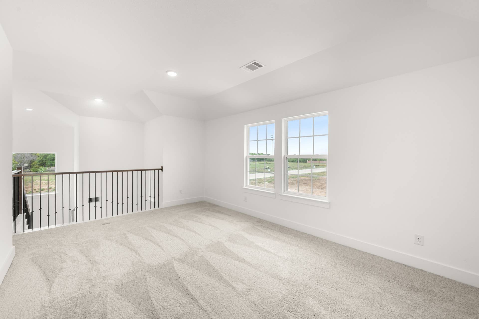 Spacious game room with carpeted floor and large windows overlooking outdoor scenery.