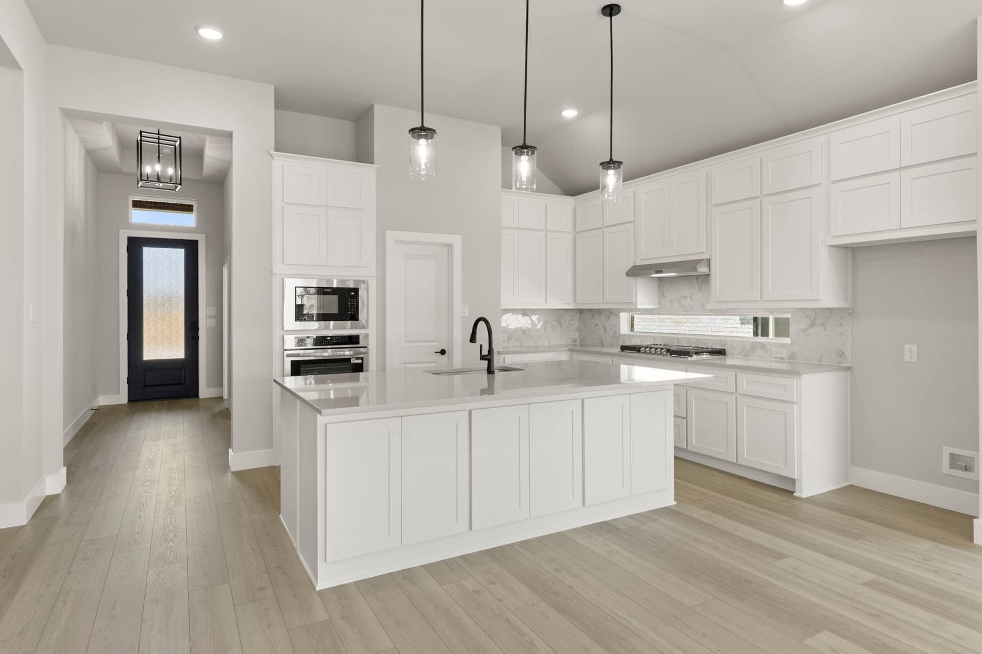 Modern kitchen with white cabinetry, large island, and pendant lighting.