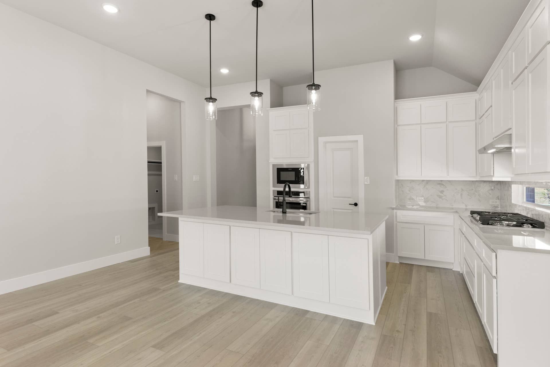Modern kitchen with white cabinetry, island, and pendant lighting.