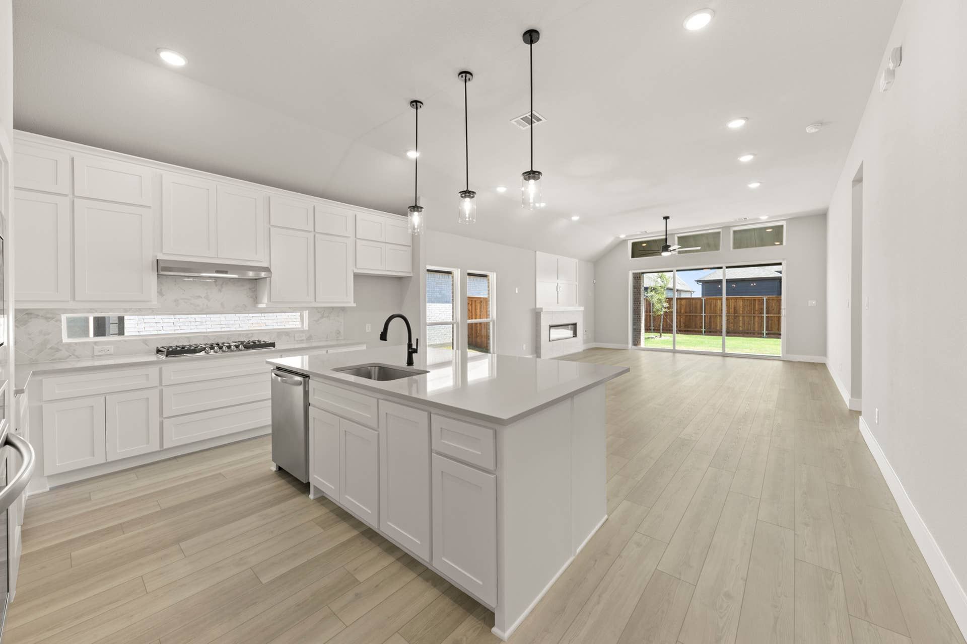 Modern open-concept kitchen with island, pendant lighting, and large sliding glass doors.