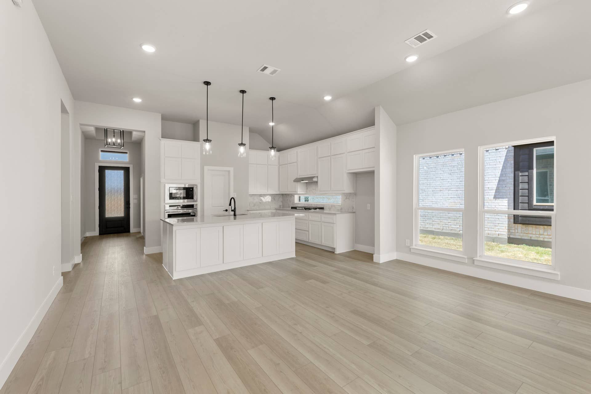 Spacious modern kitchen with white cabinetry, island, and hardwood flooring.