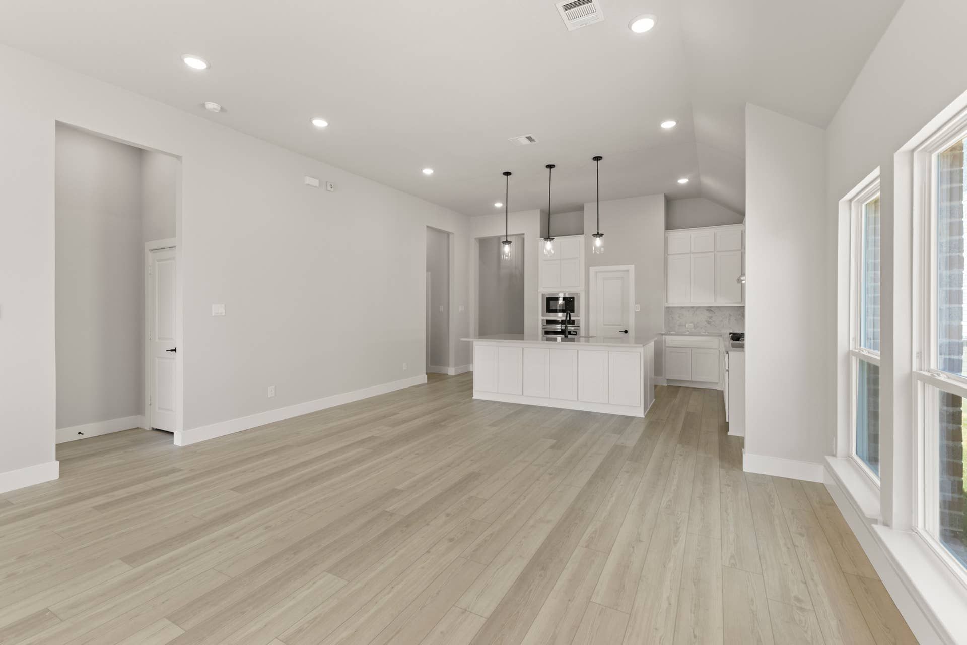 Spacious open-plan kitchen and dining area with modern fixtures and wood flooring.