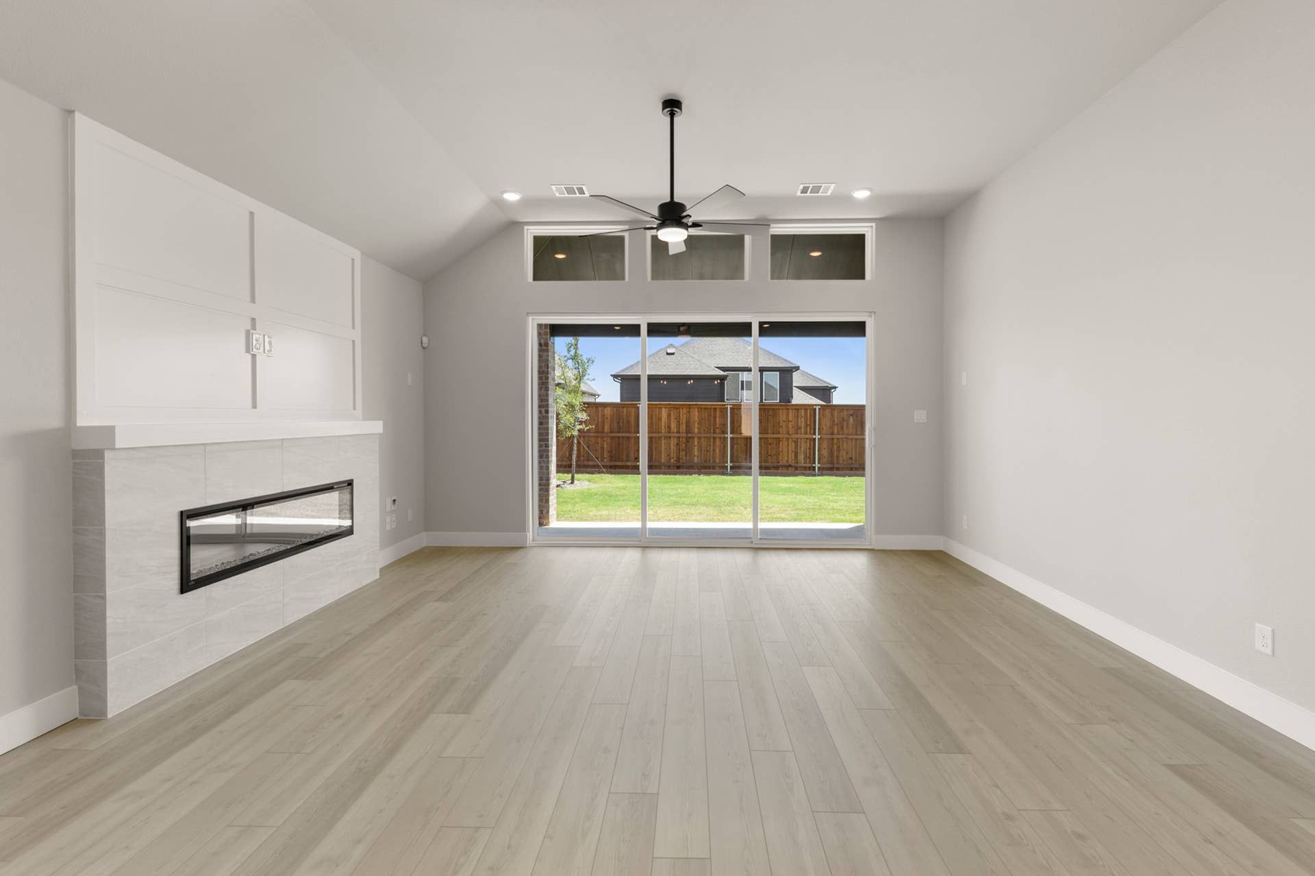 Spacious living room with modern fireplace and large sliding glass doors to backyard.