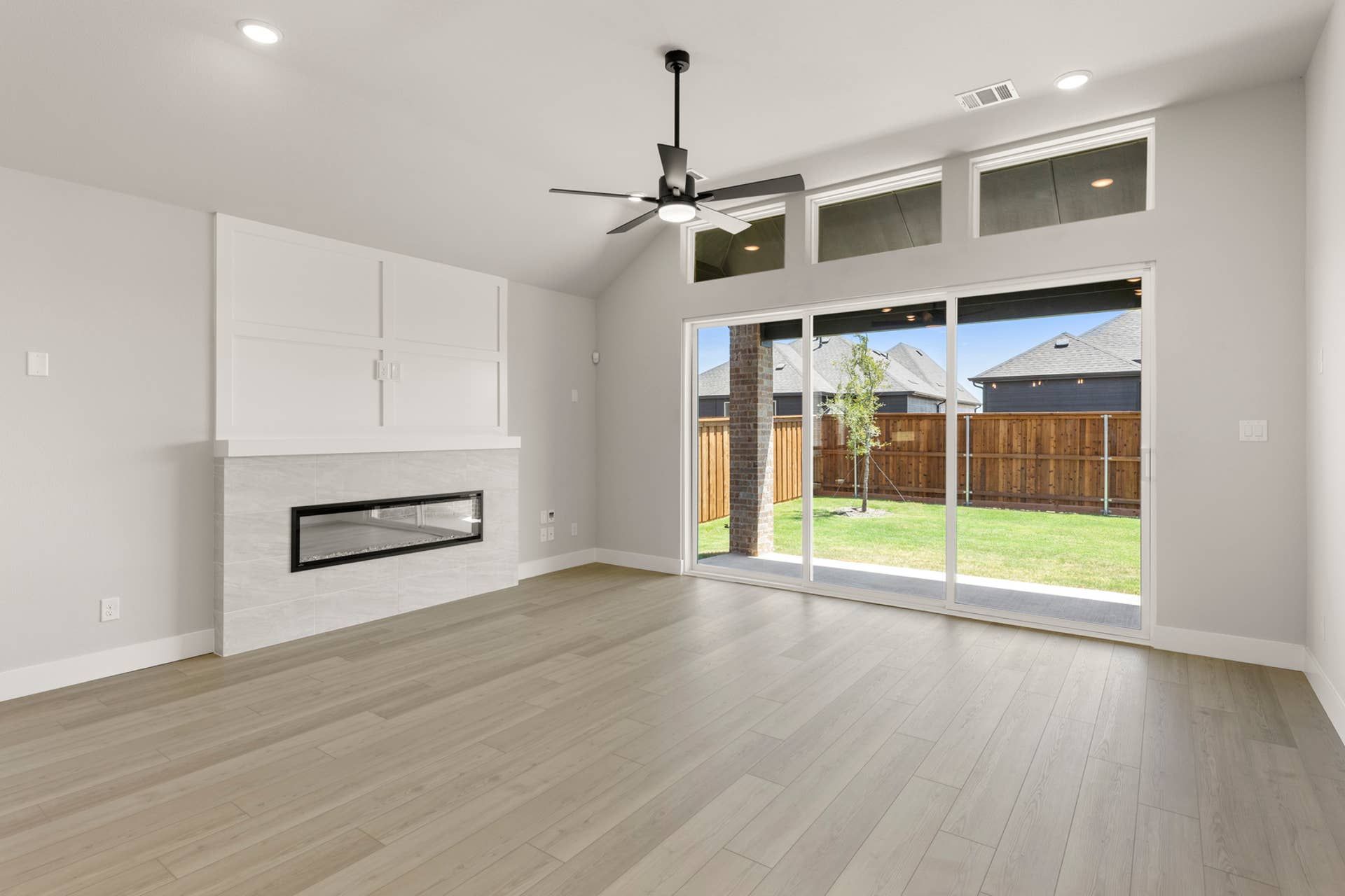 Spacious living room with modern fireplace and large sliding glass doors to backyard.