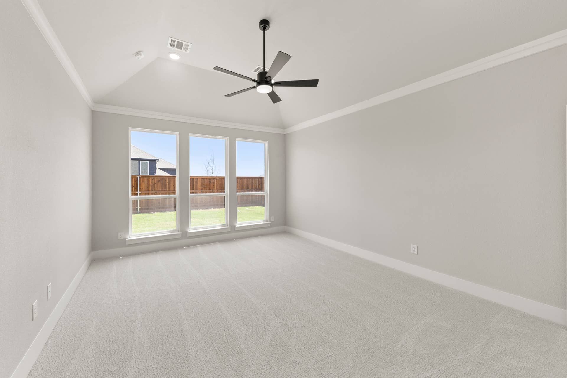 Spacious bedroom with large windows, ceiling fan, and neutral carpeting.