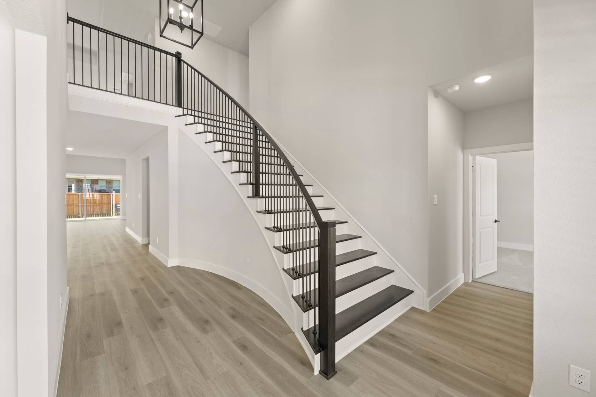 Spacious modern entryway with elegant curved staircase and wood flooring.